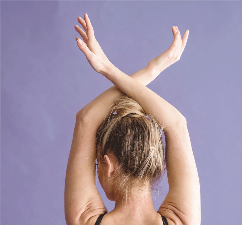 Back of woman in elegant yoga pose with arms raised. Radiant skin. 